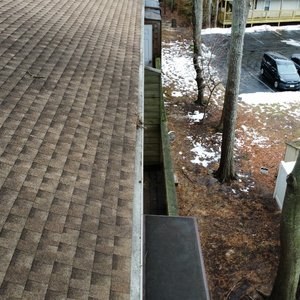 Drone view along a condominium roof showing the shingles and gutter line from above