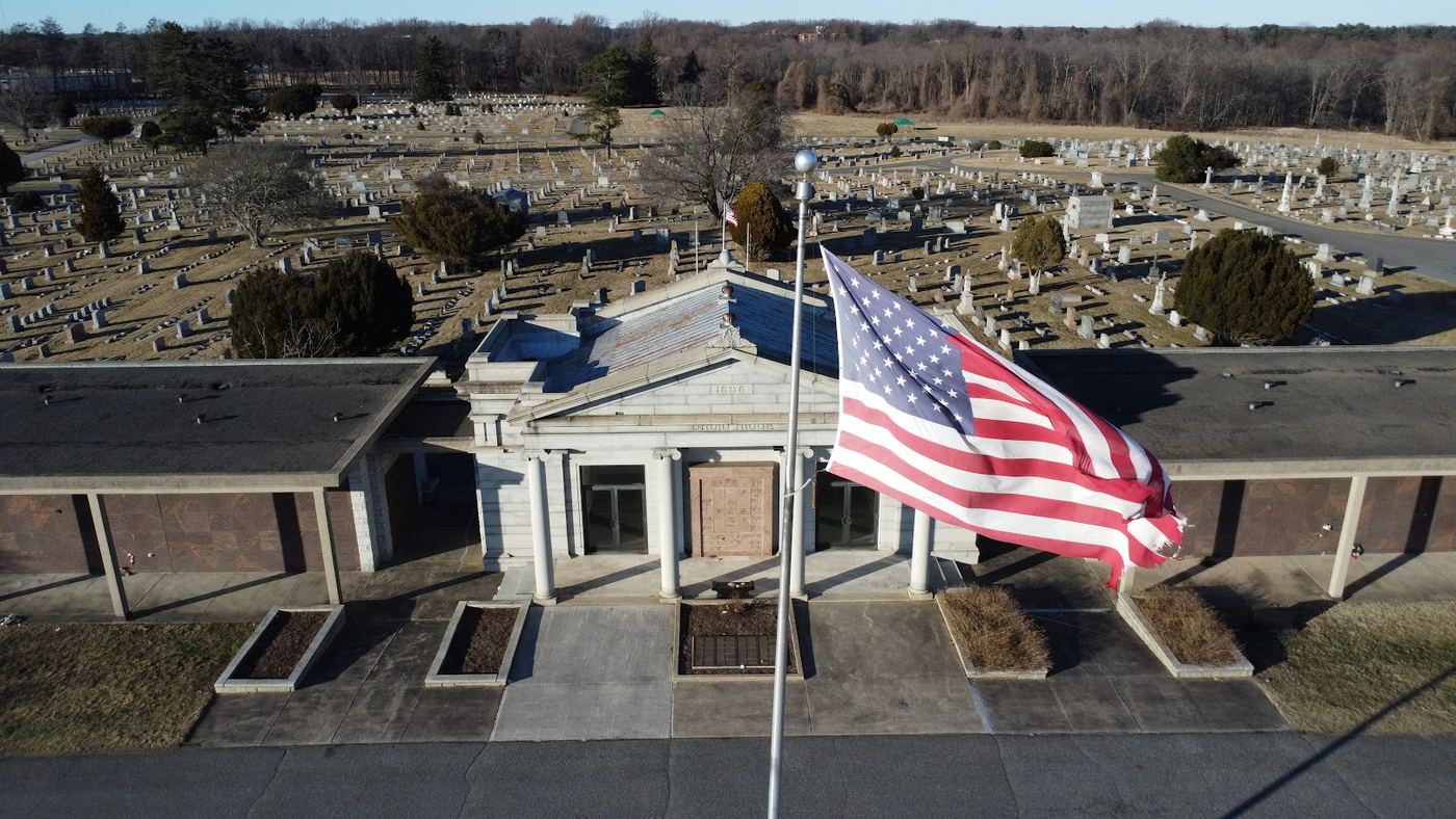 Drone photo of a historic columned building with an American flag in front and its grounds stretching behind